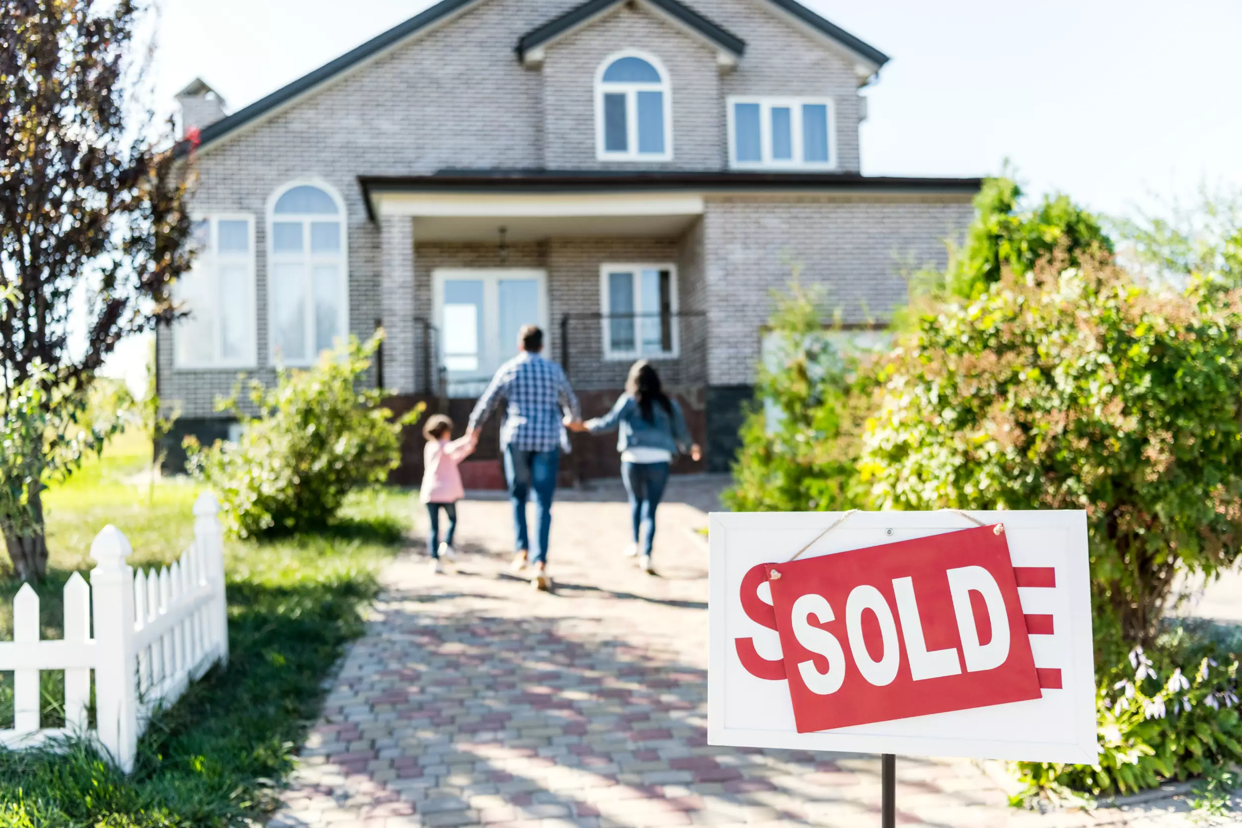 A family walking to their new home with a sold sign in front